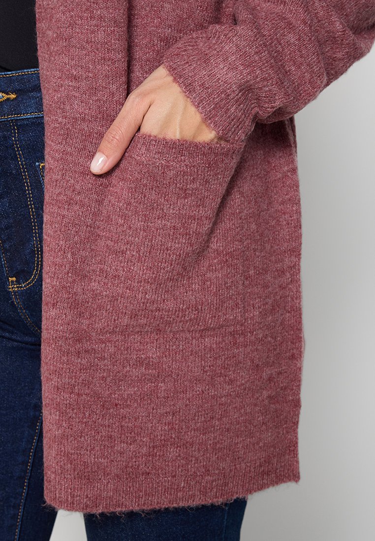Cárdigan de punto burdeos con un corte relajado, mangas largas y un bolsillo lateral, exhibido sobre un fondo neutro.