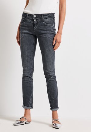 Smala jeans i mörkgrå denim, med knappstängning, framfickor och uppvikta ben. Matchas med glänsande silvriga slip-on skor.