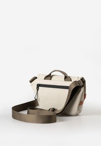 Beige Canvas-Umhängetasche mit einem abnehmbaren braunen Gurt, ausgestattet mit einer vorderen Reißverschlusstasche und einem obereren Griff für eine einfache Tragbarkeit.