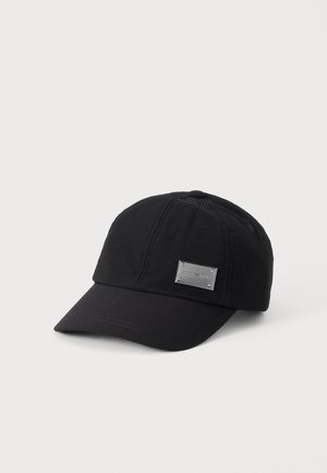 Musta tekstuuri baseball-lippalakki, jossa kaareva lippa ja pieni suorakulmainen metallinen logolevy etuosan oikealla puolella.