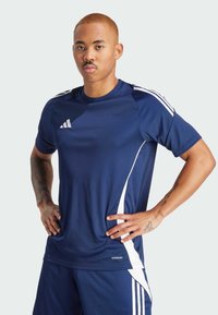 Marineblauw sportshirt met witte accenten en strepen, gemaakt van een gladde, ademende stof. Voorzien van een ronde hals en korte mouwen.