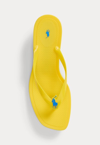 Tongs jaunes avec semelle texturée et logo joueur de polo bleu sur la bride et le talon, présentées sur un fond blanc.