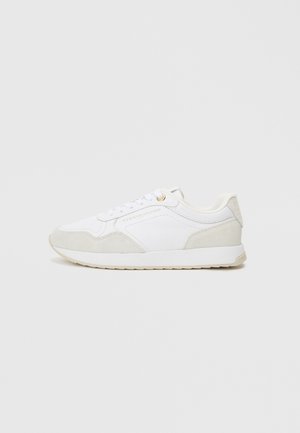 White sneakers with textured suede accents, a lace-up design, and subtle logo detail. The sole is cushioned, providing comfort and support.