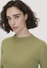 Olivgrüner, gerippter Strickpullover mit hohem Kragen und strukturierter Oberfläche. Verfügt über lange Ärmel und eine enganliegende Silhouette.