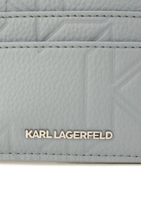 Gray textured leather featuring embossed patterns and silver "KARL LAGERFELD" branding at the bottom. Visible stitching detail.