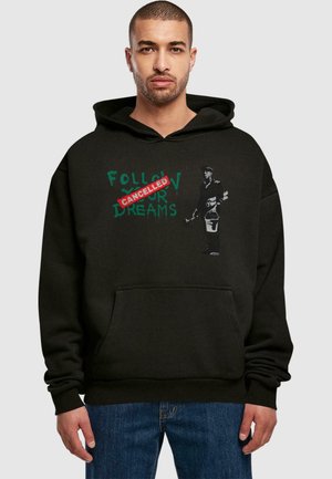 Black hoodie featuring a green graphic with the text "FOLLOW YOUR DREAMS" crossed out in red and a figure on the left holding spray paint.