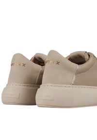 Sneaker beige in pelle liscia e suede, con una suola in gomma spessa, marchio dorato e design minimalista.