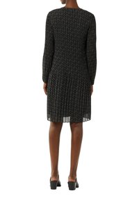 Schwarzes Kleid mit langen Ärmeln, plissiertem Design, strukturiertem Stoff und weißem Blumenmuster, mit rundem Ausschnitt und mittellanger Saumlänge.