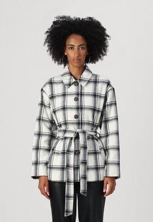 White and black plaid jacket with a collared neckline, button front, and belted waist. Made from a textured fabric with long sleeves.