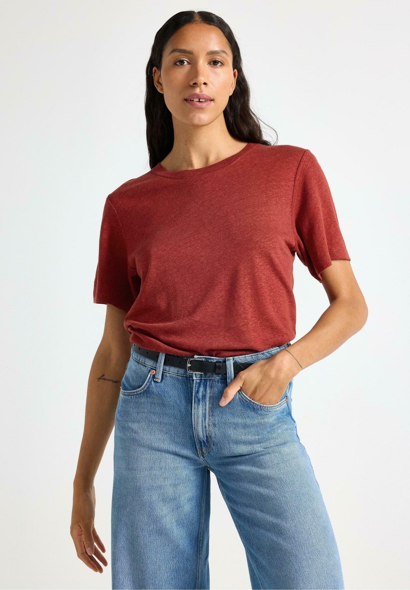 Rød kortærmet T-shirt med rund halsudskæring, kombineret med lys blå højtaljede jeans. Har en afslappet pasform og blød tekstur.