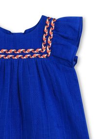 Blauwe gemêleerde stoffen jurk met korte gerimpelde mouwen en gevlochten afwerking in oranje, wit en blauw rond de vierkante halslijn.