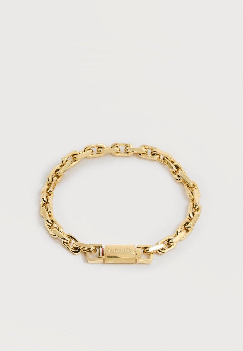 Βραχιόλι αλυσίδας σε χρυσό τόνο με ορθογώνιο κούμπωμα χαραγμένο με τη λέξη "HILFIGER" και μικρές λεπτομέρειες σε κόκκινες, λευκές και μπλε ρίγες.