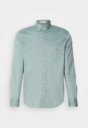 Chemise boutonnée à manches longues en tissu vert clair, dotée d'une poche poitrine et d'une texture subtile. Col classique avec des boutons blancs.