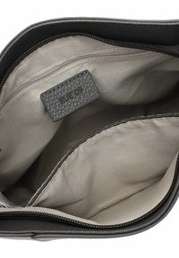 Intérieur d'un sac en cuir noir avec un design spacieux, doublure beige lisse, poche zippée et une étiquette texturée portant "RUE'09."
