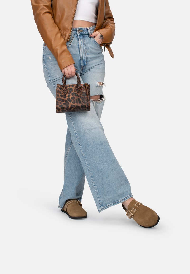 Giacca di pelle marrone, top bianco, jeans chiari strappati, scarpe marroni senza lacci, in mano una piccola borsa a stampa leopardata.