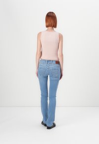 Ανοιχτό ροζ ριμπαριστό τοπ με εγκοπές, συνδυασμένο με ανοιχτό μπλε εφαρμοστά τζιν με πίσω τσέπες και καφέ δερμάτινη ετικέτα.