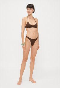 Brown bikini set with triangular top and low-rise bottom. Smooth texture, minimalistic design, halter neck straps, and no embellishments.