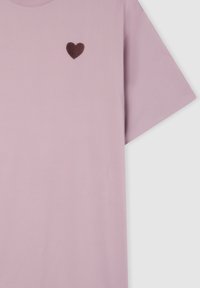 T-shirt in cotone rosa chiaro con un piccolo cuore ricamato in marrone scuro sul lato sinistro del petto. Maniche corte e design con collo rotondo.