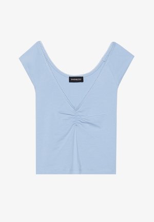 Top scurt de culoare albastru deschis, realizat dintr-un material moale, cu un în față plisat, decolteu în formă de cerc și margine ondulată în jurul decolteului.