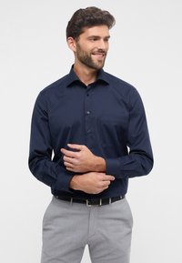 Marineblauwe button-up overhemd met een enkele borstzak, lange mouwen en een gladde textuur. Bevat een standaard kraag en knoopmanchetten.