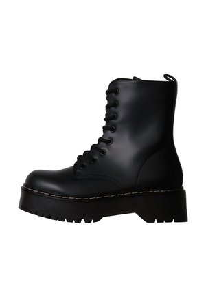 Botte de combat noire en cuir à lacets, avec semelle épaisse à rainures et languette arrière, vue de profil sur fond blanc.