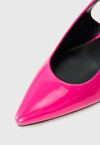 Sapato de salto alto feminino em rosa choque brilhante, com biqueira apontada e interior preto, apresentado em close contra um fundo branco.