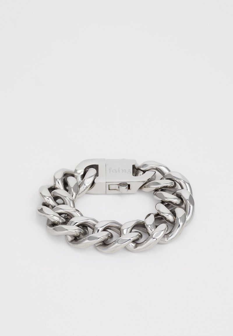 Paks hõbedane metallketi käevõru, millel on ristkülikukujuline lukk, millele on graveeritud "fainz", lamades tasasele valgele taustale.