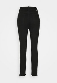 Svarta högmidjade skinny jeans med bakfickor och rå kantdetalj vid bensluten mot en vit bakgrund.