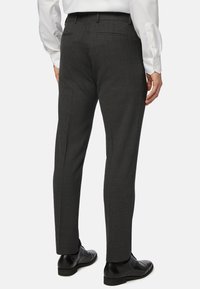 Sive elegančne hlače z teksturirano tkanino, ki vključujejo slim fit, ravno sprednjo stran in dva zadnja žepa. Ujemajo se z črnimi čevlji.