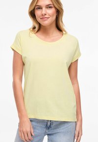 Κίτρινη κοντομάνικη μπλούζα με στρογγυλή λαιμόκοψη, κατασκευασμένη από μαλακό υλικό, με ρεβέρ στα μανίκια και άνετη εφαρμογή. Καθημερινό σχέδιο.