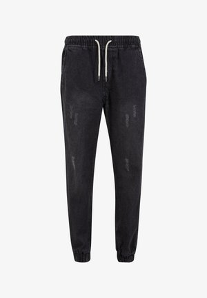 Černé denimové joggers s elastickým páskem a stahovací šňůrkou, s uvolněným střihem a roztrhnutými detaily na látce.