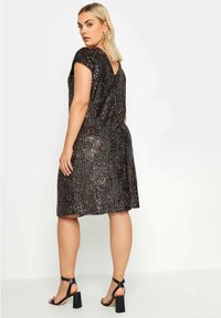 Musta paljeteilla koristeltu mekko, jossa on hihat ja V-mallinen selkäkaulus. Mekossa on rento istuvuus ja polveen ylettyvä helma. Yhdistetty mustien nilkkureiden kanssa.