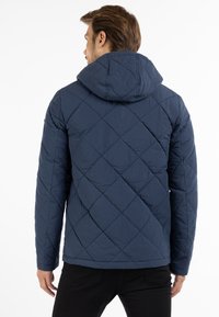 Marineblå quiltet jakke med hætte, der har et diamantmønster, tekstureret stof og en lige pasform med elastiske manchetter.