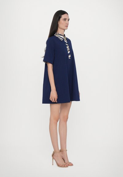 Abito navy con una silhouette ampia, maniche corte e una chiusura a bottoni, caratterizzato da un colletto a righe e dettagli decorativi.
