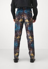 Multicolored patterned trousers featuring a butterfly design in shades of blue, yellow, and black. Tailored fit with slip pockets.
