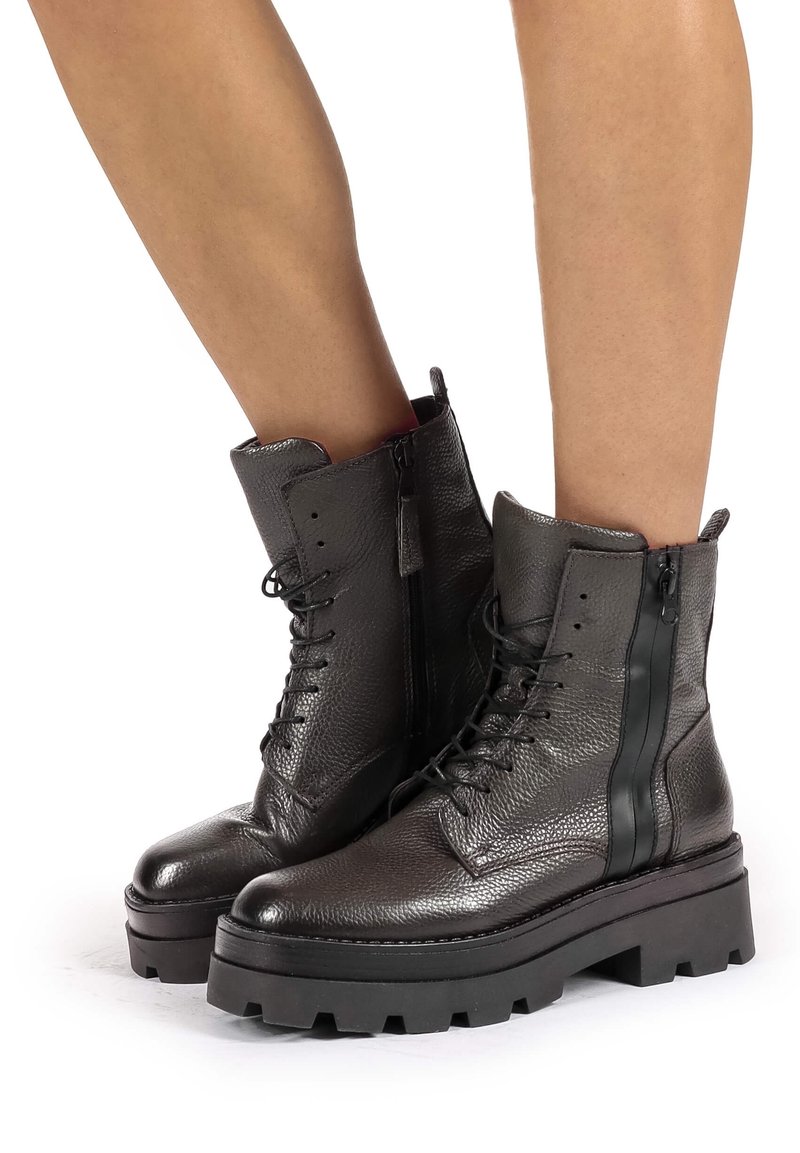 Bottes cheville en cuir noir avec une finition texturée, dotées d'un laçage avant et d'une fermeture éclair latérale pour un enfilage facile. Semelle plateforme épaisse et robuste.