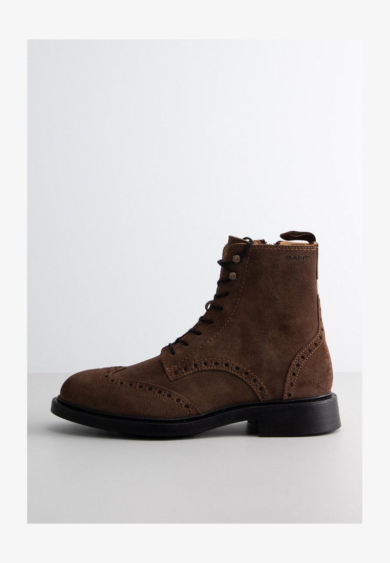 Braune Wildleder-Ankelstiefel mit Schnürdesign, Brogue-Details und einer schwarzen Gummisohle. Verfügt über einen seitlichen Reißverschluss für ein einfaches Anziehen.