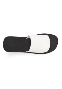 Melnas slaidu sandales ar plašu baltu auduma jostu, mīkstu kāju daļu un platu zoli. Minimalistisks dizains ar gludu virsmu.