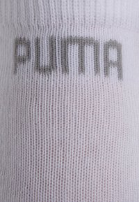 White fabric with gray knit text spelling "PUMA" horizontally across the center.