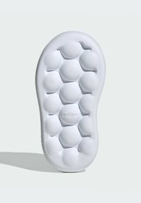 White foam sole with a bubble-like pattern, featuring embossed "adidas" logo. Smooth texture and rounded shape for comfort.