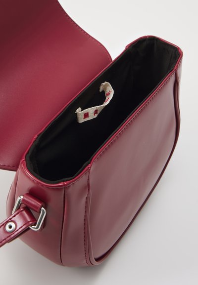 Borsa in pelle bordeaux con una texture liscia, dotata di un interno in tessuto nero e un piccolo etichetta. Include una tracolla con fibbia argentata.