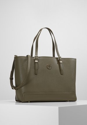 Sac cabas structuré vert olive avec doubles poignées, bandoulière ajustable et détail logo métallique rond à l'avant.
