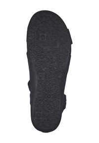 Black rubber shoe sole featuring a flower and geometric pattern, marked with "Dockers by Gerri" and size 38. Flat and textured surface.