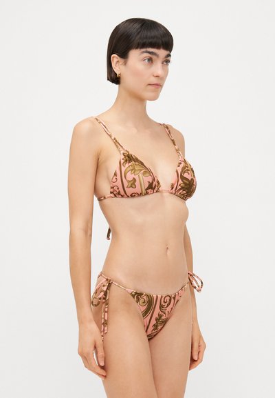 Rozā bikinis ar sarežģītiem brūniem ziedu motīviem. Tam ir trīsstūra formas tops un regulējamas sānu saites apakšdaļā, izceļot gludu tekstūru.