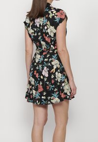 Vestido envolvente floral con mangas cortas, fondo negro, flores coloridas en rosa, blanco y azul, y una cintura ajustada con falda acampanada.