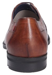 Scarpa in pelle marrone con una texture liscia, tacco rotondo, suola in gomma nera e dettagli di cucitura discreti. Fabbricata a Roma.