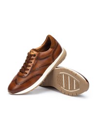 Bruine leren sneakers met een gestructureerde bovenkant, witte tussenzool en rubberen buitenzool met een golvend profiel. Accenten met decoratieve stiksels.