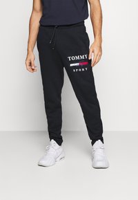 Schwarze Sweatpants aus Baumwolle mit einem weißen "TOMMY SPORT"-Logo, elastischem Bund mit Kordelzug und schmal zulaufenden Säumen.