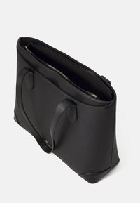 Musta nahkainen kassi, jossa on teksturoitu pinta, vetoketjukiinnitys ja kaksi kahvaa. Sisäpuoli on avara ilman näkyviä taskuja tai osastoja.