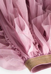 Rosa Tüllstoff mit goldenen Glitzerakzenten, gerüschter Textur und einem breiten, gewebten goldenen Band am unteren Ende. Weiche und fließende Optik.